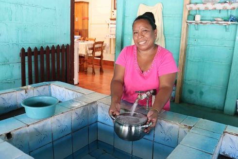 Madre recogiendo agua en una olla. Agua y Saneamiento - Banco Interamericano de Desarrollo - BID 