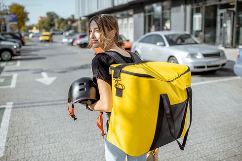 A young female courier standing with yellow backpack. Innovation and Social Security - Inter-American Development Bank - IDB