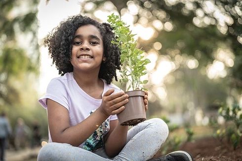 A child holding a plant. Investment - Inter-American Development Bank - IDB