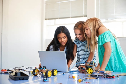 Group of girls looking at a laptop. Education - Inter-American Development Bank - IDB