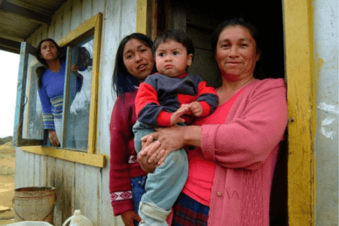 Group of people standing in their house door. Gender Equity - Inter-American Development Bank - IDB