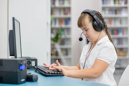 A child wearing headphones and using a computer. Economic inclusion - Inter-American Development Bank - IDB