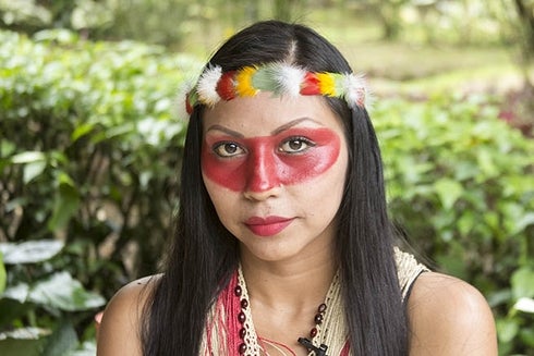 A woman with red face paint and feathers in her hair. Development - Inter-American Development Bank - IDB