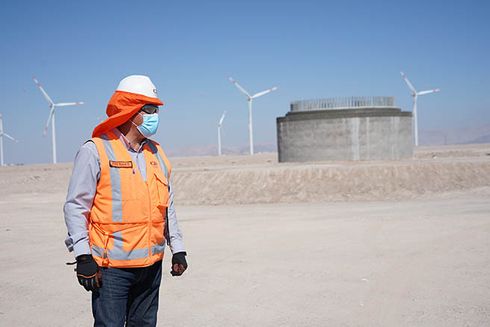 A person wearing safety gear and wind turbines in the background. Regional Cooperation - Inter-American Development Bank - IDB