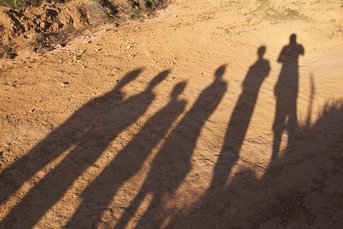 Shadows of people on a dirt road