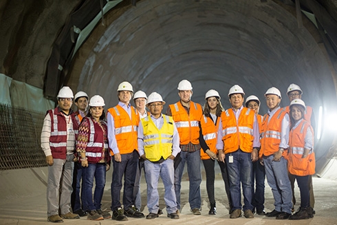 A group of people in safety suits with a tunnel at background