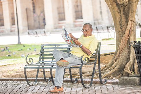 A man sitting on a bench reading a newspaper