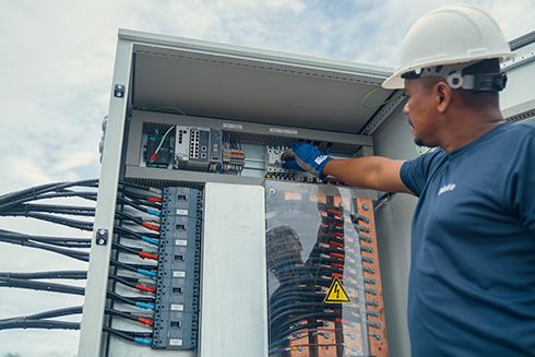A man wearing safety gear working on a electrical box