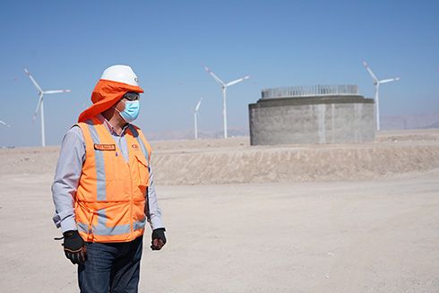 A person in safety gear with wind turbines in background