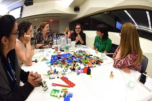 A group of people sitting around a table with building blocks. housing - Inter-American Development Bank - IDB