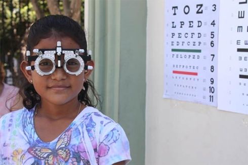 A child with an eye test device. Equity - Inter-American Development Bank - IDB