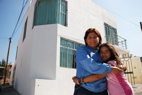 a woman and a child hugging in front of a white building