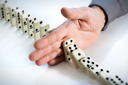 A hand stopping dominoes