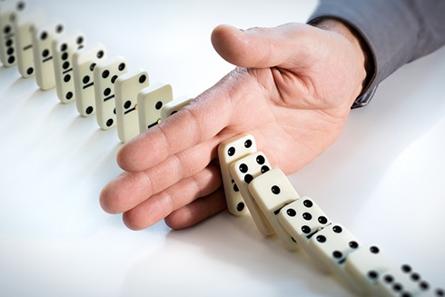 A hand stopping dominoes