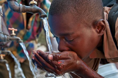 boy drinking water from faucet with hands