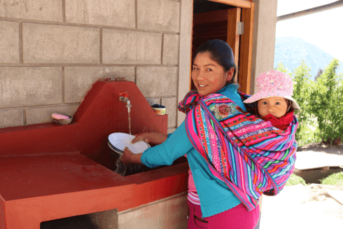 A person and child washing dishes. Water and Sanitation - Inter-American Development Bank - IDB