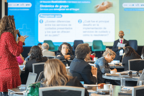 a group of people sitting at tables in front of a large screen Service - Inter-American Development Bank - IDB