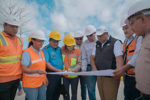 a group of people wearing hard hats looking at a piece of paper