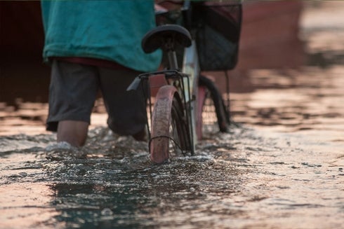 A person walking on a bicycle in water - Inter-American Development Bank - IDB