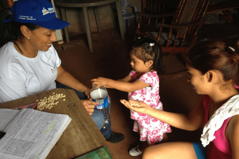 A person and a child feeding. Education - Inter-American Development Bank - IDB