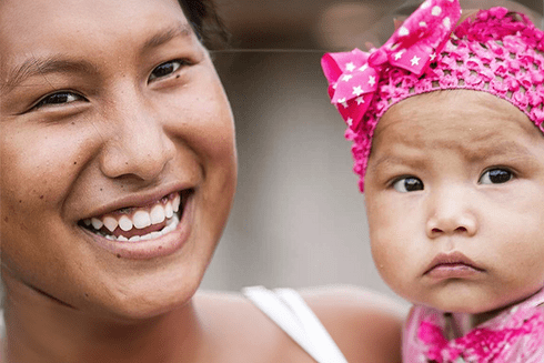 a person smiling with a baby Innovative - Inter-American Development Bank - IDB