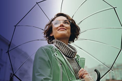 a person wearing glasses and a green jacket holding an umbrella Gender - Inter-American Development Bank - IDB
