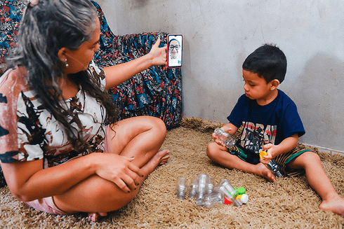 A person taking a picture of a child sitting on the floor. Inclusion - Inter-American Development Bank - IDB