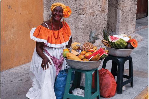 A person in an orange dress sitting next to a bowl of fruit - Finance - Inter-American Development Bank - IDB