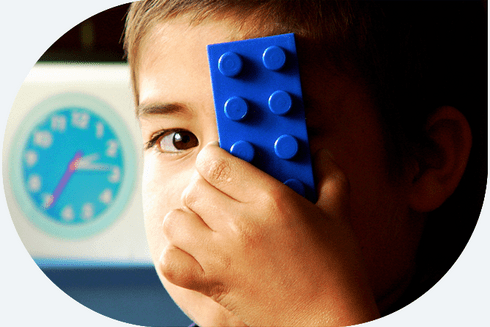 A child holding a blue block over his eye - Inter-American Development Bank - IDB