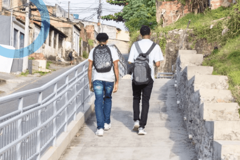 Two teenage students walking through a low-income neighborhood in Brazil, highlighting the impact of IDB projects in improving community development through policymaking - Inter-American Development Bank - IDB - Development Effectiveness