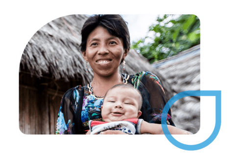 Smiling mother holding her baby in a rural Indigenous community, symbolizing the impact of IDB’s investments in maternal and child health across underserved areas in Latin America - Inter-American Development Bank IDB - Development Effectiveness