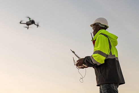 Male worker watching a drone flying in the sky - Inter American Development Bank - Water and Sanitation