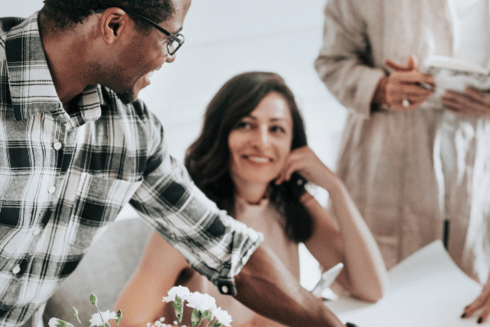 Woman smiling in an office with two men - Inter American Development Bank - Grievances Portal