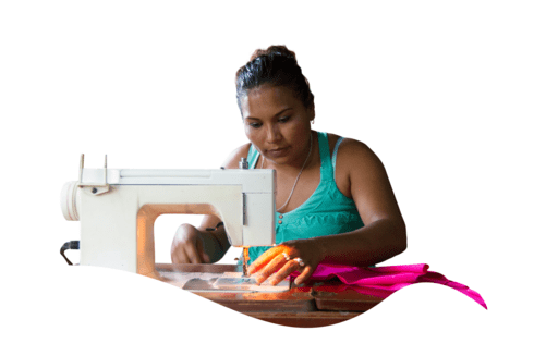 Brunette woman sitting working with a sewing machine - Inter American Development Bank - Impact Framework