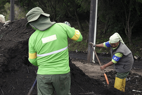 Workers with their backs to the earth piling up with shovels - Inter American Development Bank - Water and Sanitation