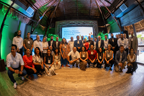 People standing and sitting smiling in a conference room - Inter American Development Bank - Amazonia