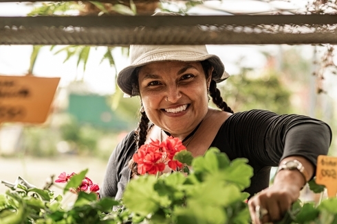 Woman smiling with a hat and flowers on the background - Inter American Development Bank - Migration