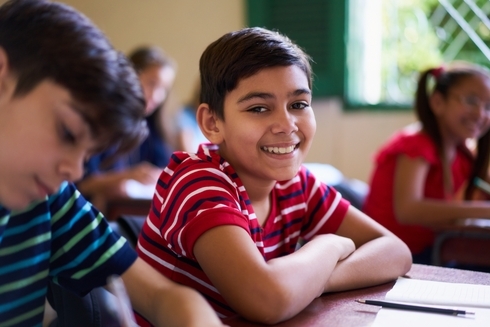 A boy smiling in a clasroom - Inter American Development Bank - Migration