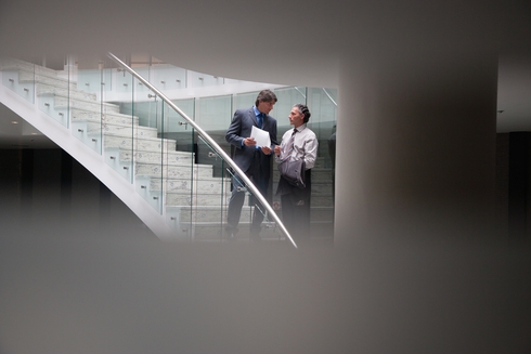 Two men standing on a staircase talking - Inter American Development Bank - Transparency
