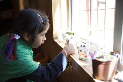 Girl playing with containers placed on a window - Inter American Development Bank - Public Sector