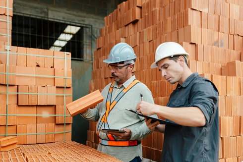 Construction workers inspecting bricks IDB
