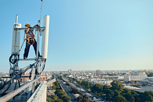 Technician working on telecommunications infrastructure above an urban area IDB