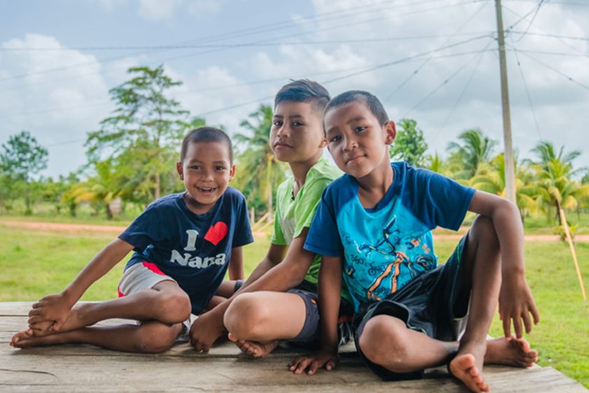 Niños sonriendo sentados en la entrada de su casa. Desarrollo rural y energía - Banco Interamericano de Desarrollo - BID 