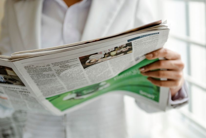 Person reading a newspaper and holding it in their hand - Inter American Development Bank - Migration
