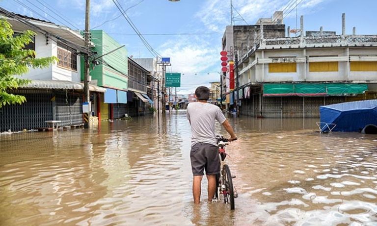 A boy on a bicycle in a flooded street. Sustainability - Inter-American Development Bank - IDB