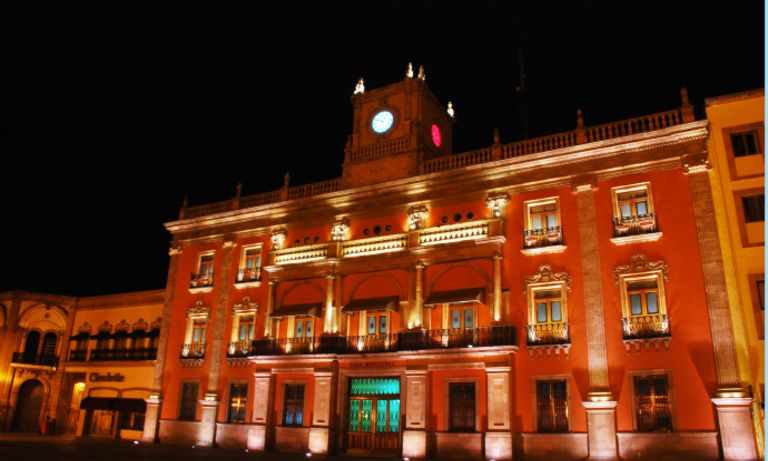 An illuminated building with a clock tower. Inter-American Development Bank