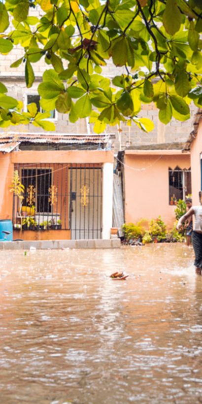 Niña corriendo en la calle de un barrio inundado. Desarrollo social y económico - Banco Interamericano de Desarrollo - BID  