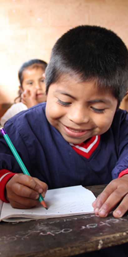 Niño en el colegio escribiendo en su cuaderno. Desarrollo social e inclusión - Banco Interamericano de Desarrollo - BID 